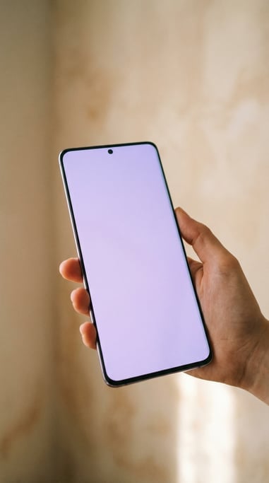 Hand holding a large-screen smartphone against a soft blurred beige background