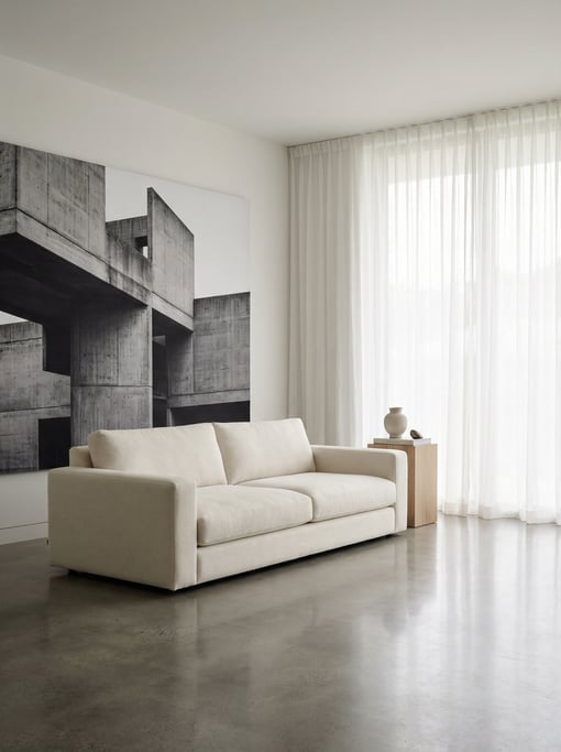 Modern minimalist living room with a single cream sofa on a polished concrete floor