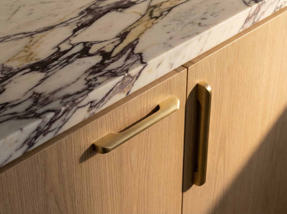 Detail of a modern kitchen showing the meeting point of a marble countertop, oak cabinetry