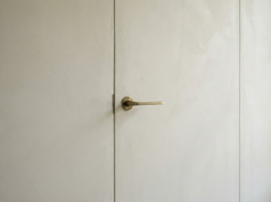 Detail of a modern door with hidden hinges, flush with the plaster wall
