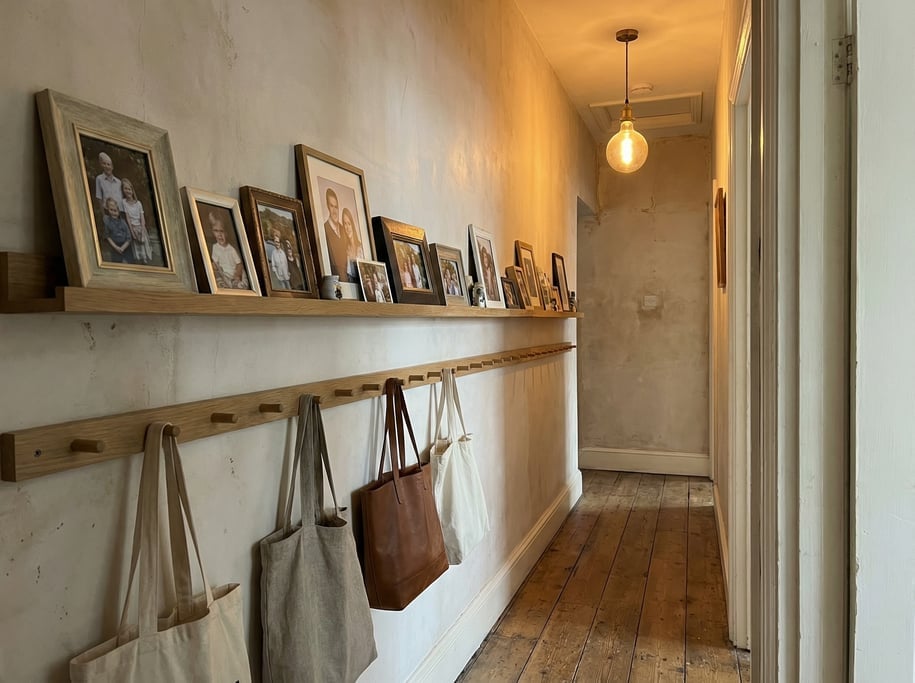 Narrow hallway with a row of framed family photos on a ledge shelf