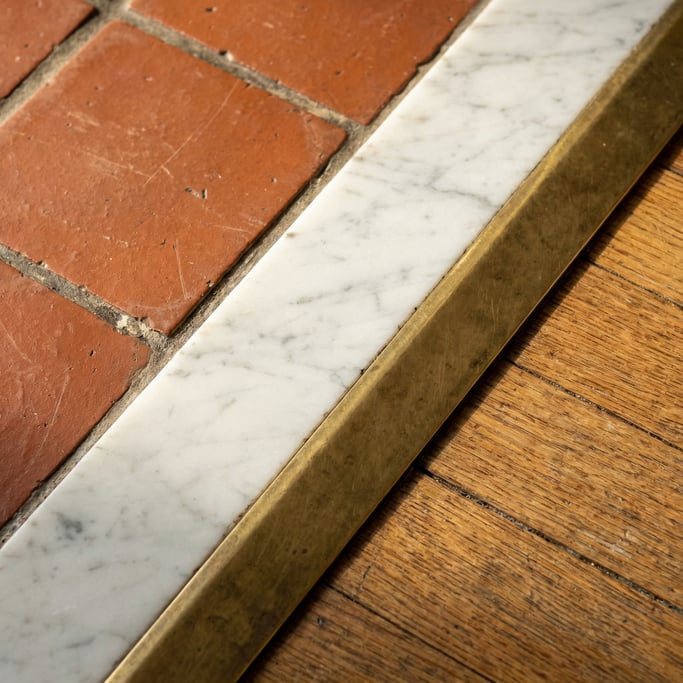 Detail of a marble threshold strip where kitchen tile meets living room hardwood