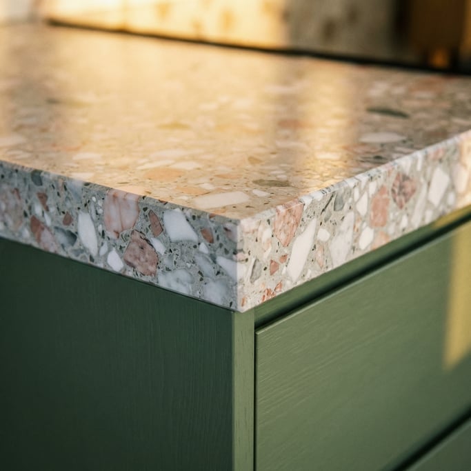 Close-up of a modern terrazzo countertop edge showing the polished aggregate in white, pink