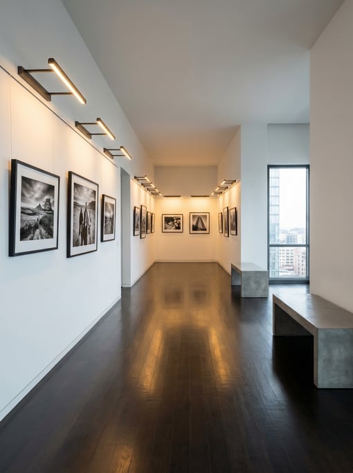 Modern gallery hallway with picture rail lighting illuminating a collection of framed photography on