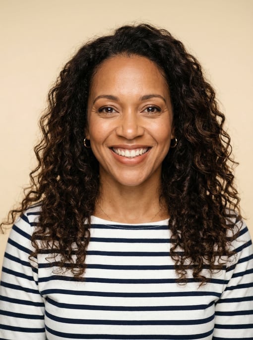 Professional studio headshot of a 40-year-old Black Caribbean woman with long loose curls in dark br