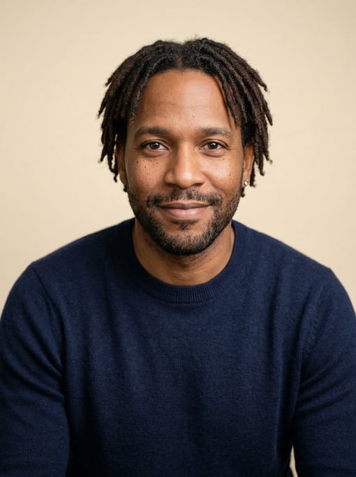 Professional studio headshot of a 37-year-old Dominican man with short locs in dark brown