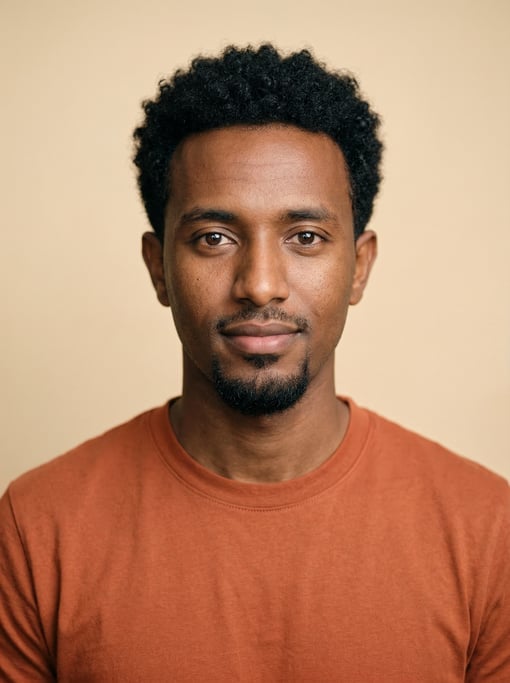 Professional studio headshot of a 25-year-old Ethiopian man with short curly black hair, a goatee