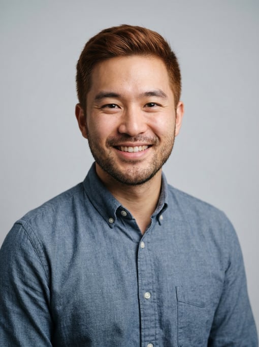 Professional studio headshot of a 26-year-old East Asian man with short red-brown hair