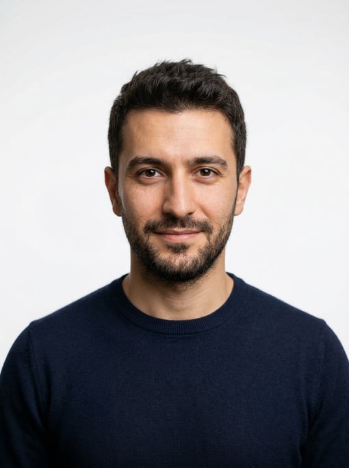 Professional studio headshot of a 29-year-old Turkish man with short textured dark brown hair