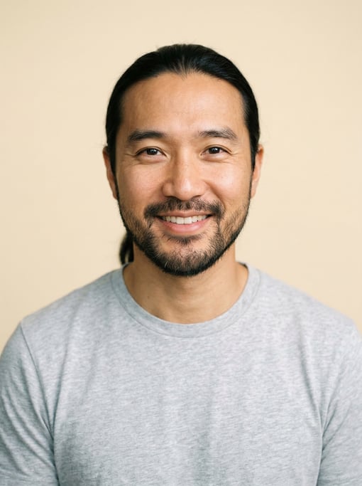 Professional studio headshot of a 39-year-old Chinese man with long straight black hair tied back