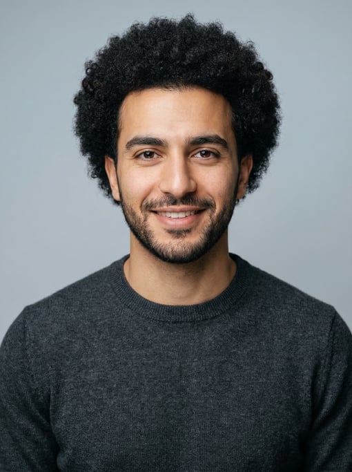 Professional studio headshot of a 26-year-old Lebanese man with a medium natural afro in black
