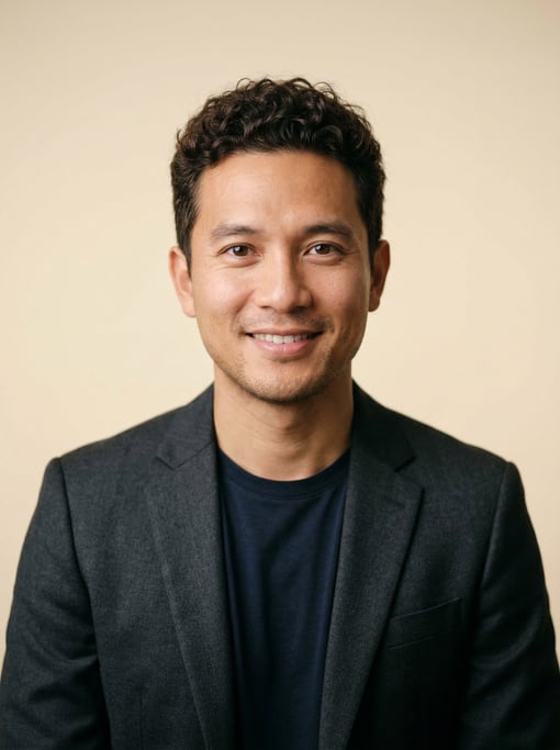 Professional studio headshot of a 33-year-old Vietnamese man with short curly dark brown hair
