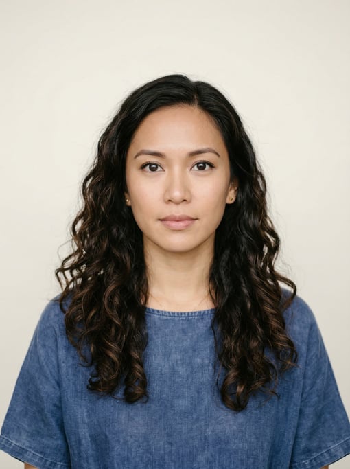 Professional studio headshot of a 31-year-old Southeast Asian woman with long loose curls in dark br