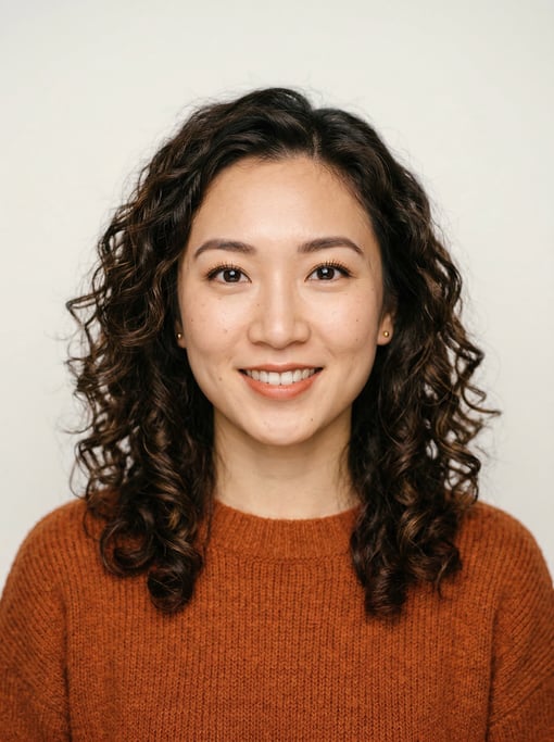 Professional studio headshot of a 24-year-old East Asian woman with shoulder-length curly dark brown