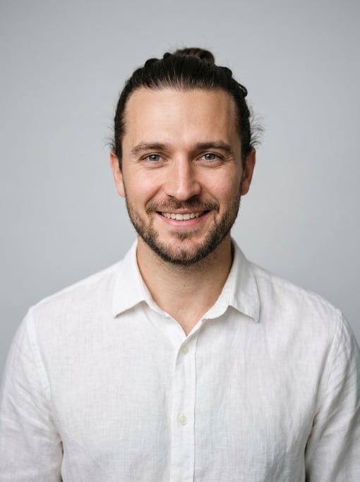 Professional studio headshot of a 30-year-old White Eastern European man with a man bun in dark brow