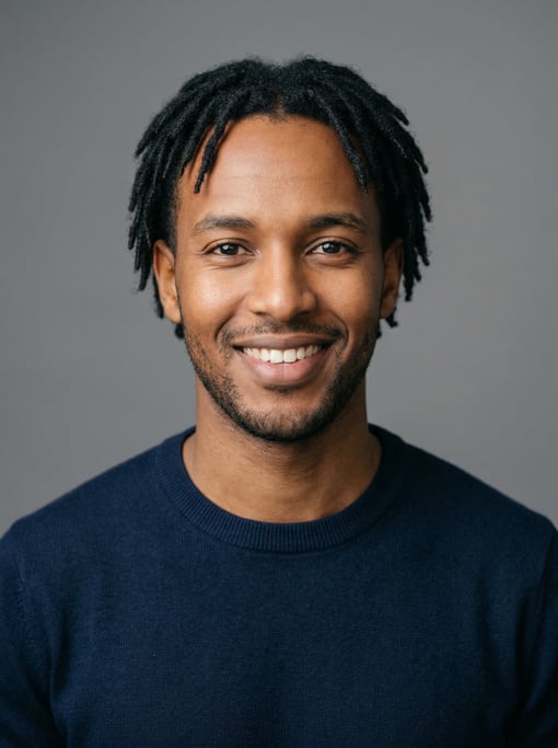 Professional studio headshot of a 27-year-old East African man with short locs in black