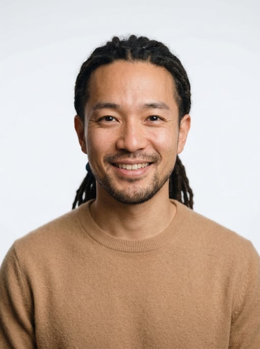 Professional studio headshot of a 30-year-old Japanese man with medium dreadlocks pulled back