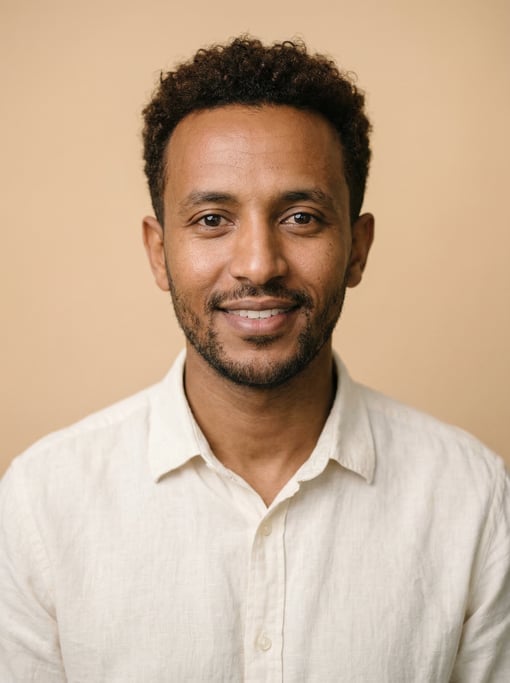 Professional studio headshot of a 31-year-old Ethiopian man with short curly dark brown hair