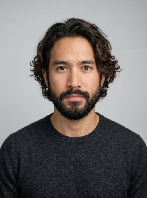 Professional studio headshot of a 32-year-old Thai man with medium-length wavy dark brown hair
