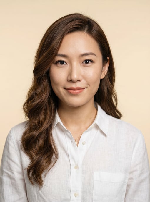 Professional studio headshot of a 28-year-old Chinese woman with a deep side part with long brown wa