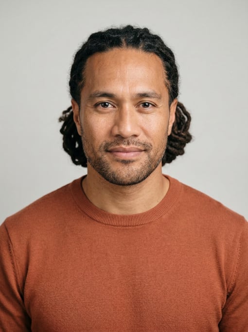 Professional studio headshot of a 39-year-old Pacific Islander man with medium dreadlocks pulled bac