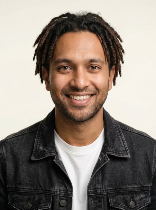 Professional studio headshot of a 31-year-old Bengali man with short locs in dark brown