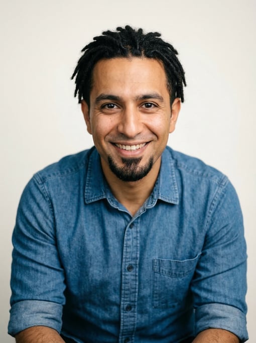 Professional studio headshot of a 33-year-old Persian man with short locs in black, a goatee