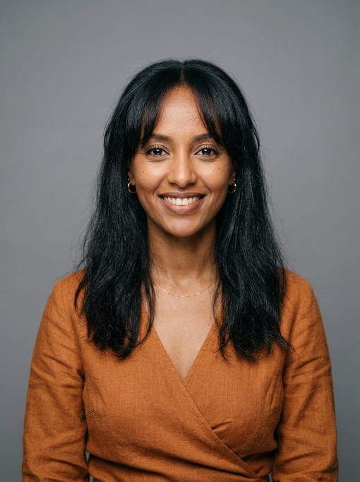 Professional studio headshot of a 30-year-old East African woman with curtain bangs with long dark h
