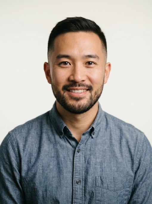 Professional studio headshot of a 31-year-old East Asian man with a short clean fade