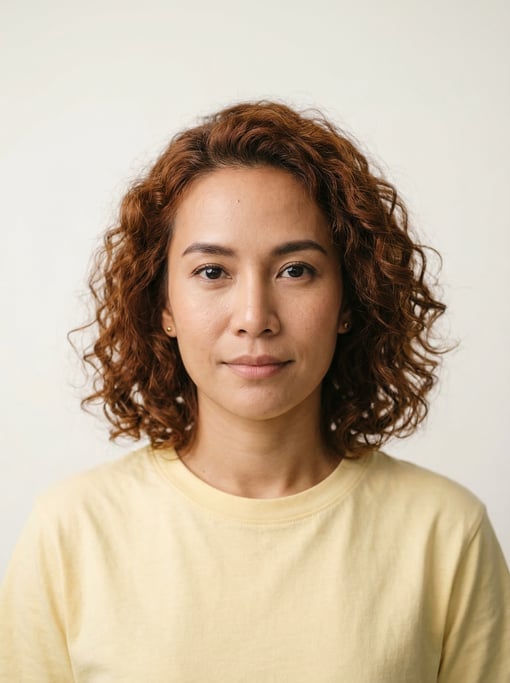 Professional studio headshot of a 32-year-old Thai woman with shoulder-length curly auburn hair
