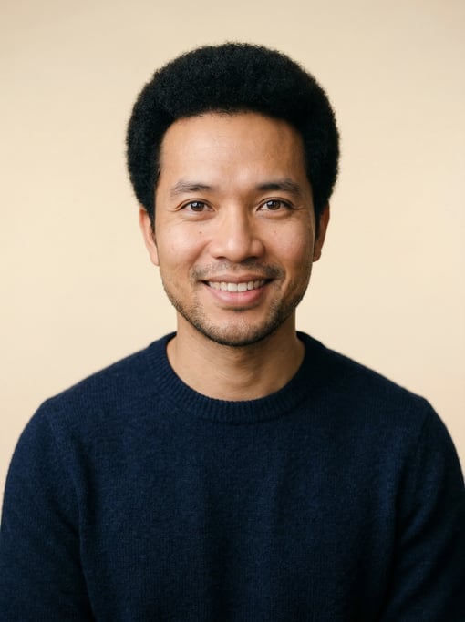 Professional studio headshot of a 34-year-old Vietnamese man with a short natural afro in black