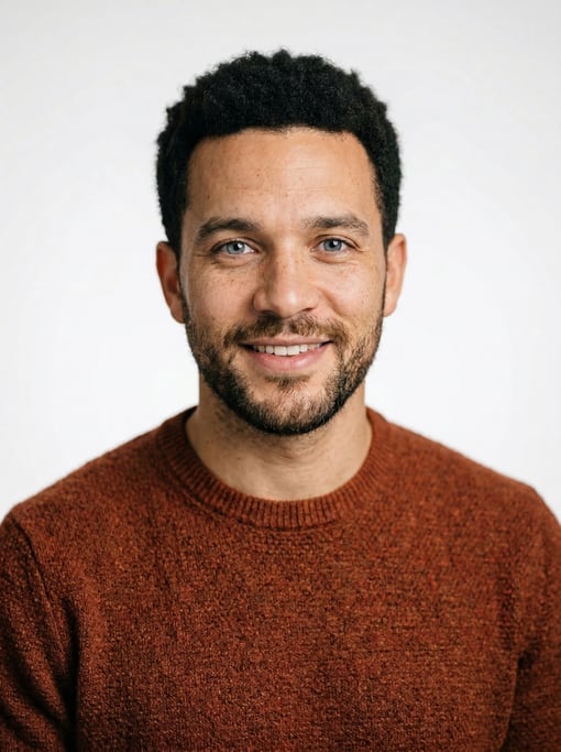Professional studio headshot of a 31-year-old White British man with a short natural afro in black