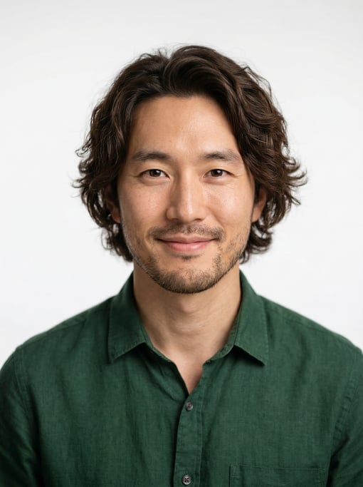 Professional studio headshot of a 31-year-old Korean man with medium-length wavy dark brown hair
