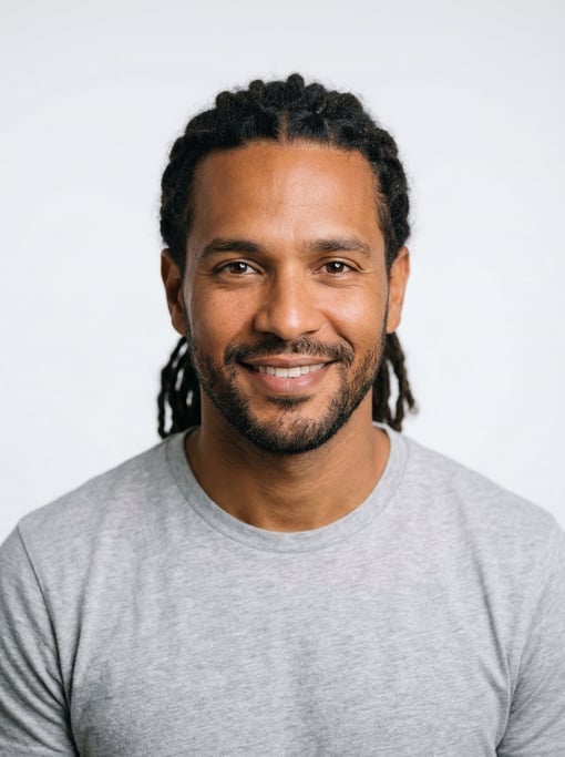 Professional studio headshot of a 34-year-old Cuban man with medium dreadlocks pulled back