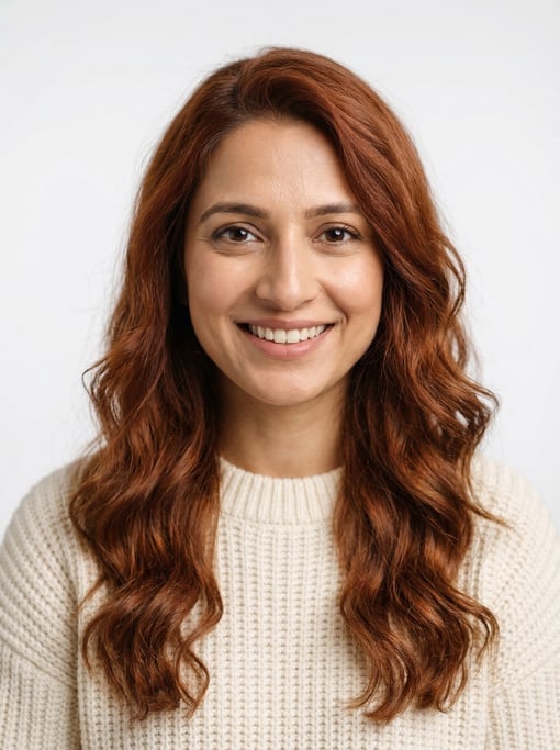 Professional studio headshot of a 32-year-old Pakistani woman with long wavy auburn hair