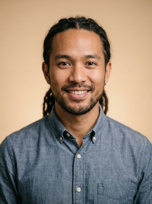 Professional studio headshot of a 30-year-old Southeast Asian man with medium dreadlocks pulled back