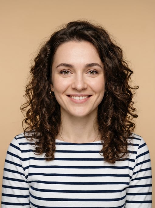 Professional studio headshot of a 26-year-old White Eastern European woman with long loose curls in