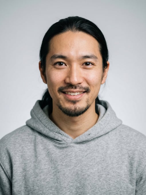 Professional studio headshot of a 29-year-old Japanese man with long straight black hair tied back