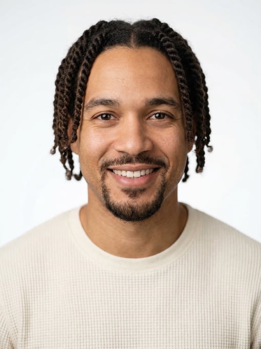 Professional studio headshot of a 30-year-old mixed-race man with twists in dark brown, a goatee