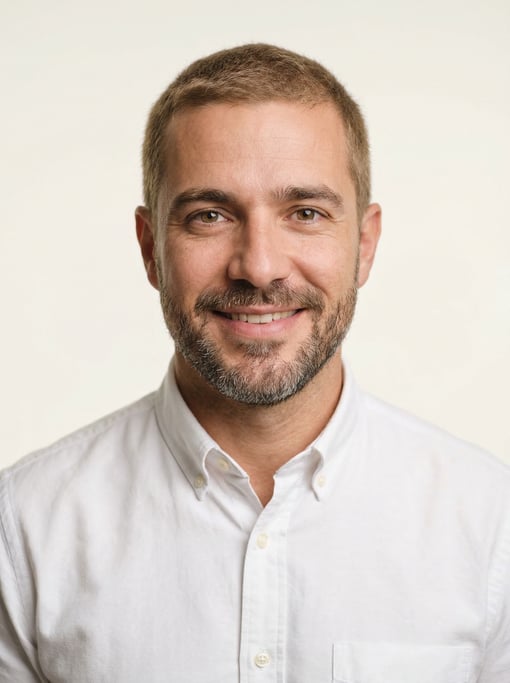 Professional studio headshot of a 38-year-old Brazilian man with short cropped sandy brown hair
