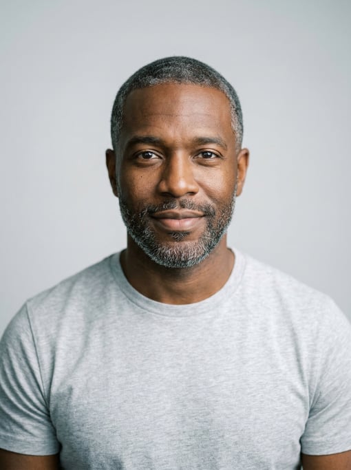 Professional studio headshot of a 33-year-old Black American man with short salt-and-pepper hair nea