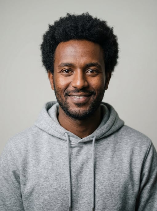 Professional studio headshot of a 26-year-old Ethiopian man with a medium natural afro in black