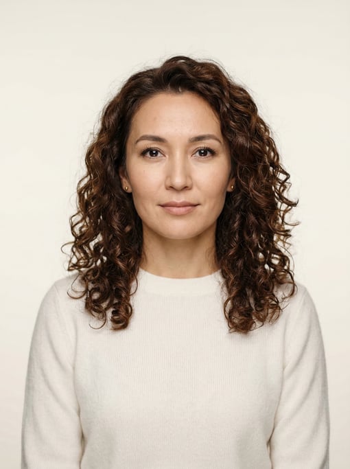 Professional studio headshot of a 33-year-old Central Asian woman with shoulder-length curly dark br
