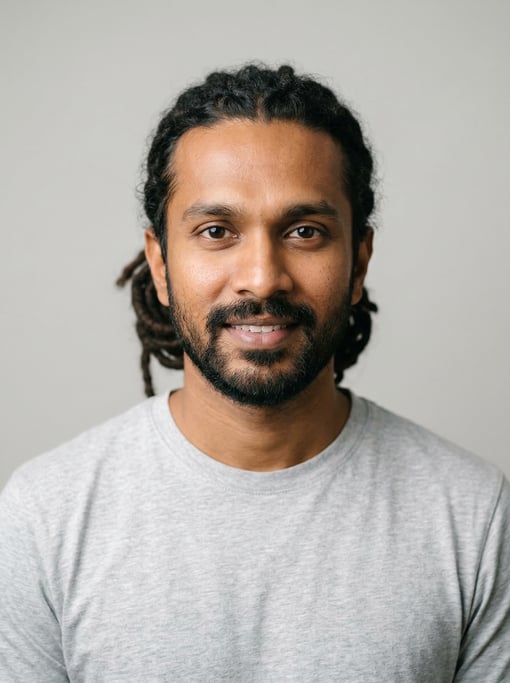 Professional studio headshot of a 34-year-old Sri Lankan man with medium dreadlocks pulled back