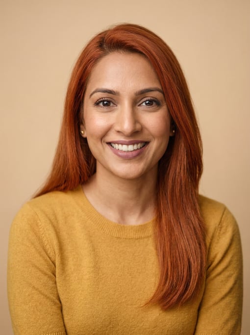 Professional studio headshot of a 35-year-old South Asian woman with long straight copper red hair