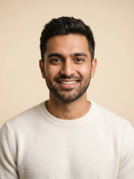 Professional studio headshot of a 28-year-old Indian man with short textured dark brown hair