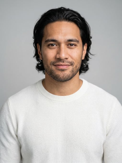 Professional studio headshot of a 26-year-old Polynesian man with medium-length wavy black hair swep