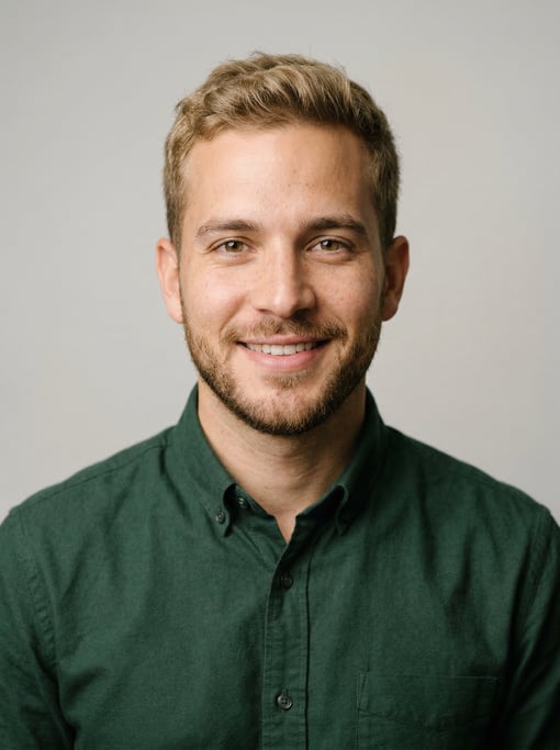 Professional studio headshot of a 26-year-old Cuban man with short dirty blonde hair