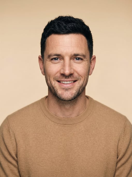 Professional studio headshot of a 37-year-old White British man with a black textured crop