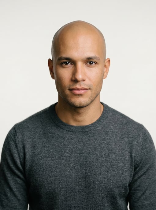 Professional studio headshot of a 24-year-old Brazilian man with a completely bald head
